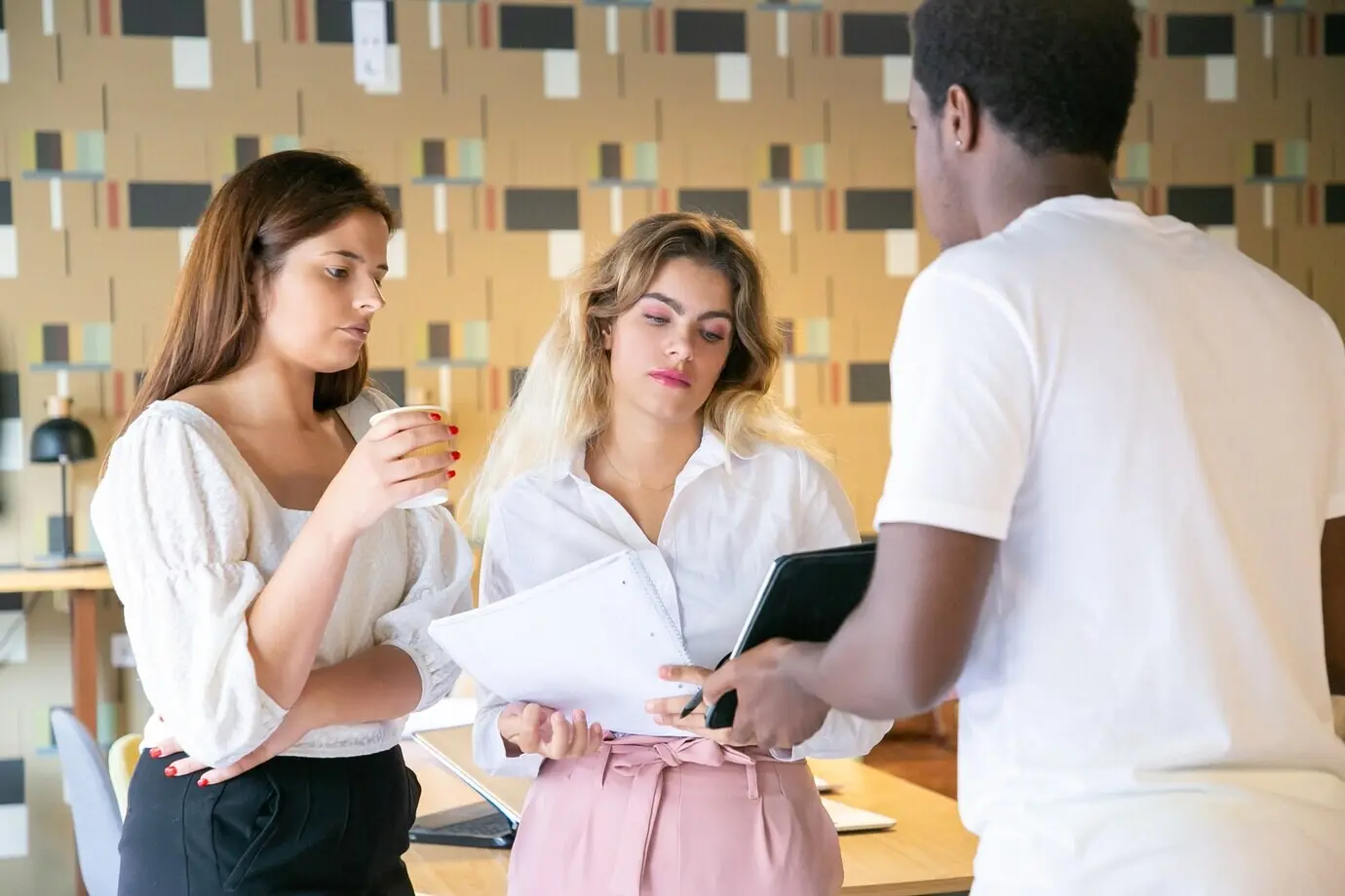 Афроамериканский мужчина демонстрирует партнёрам экран планшета.